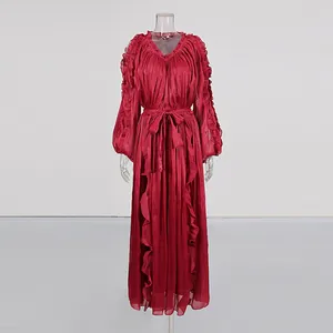 Detail of deep red pleated long dress with ruffle sleeves and tie-waist on mannequin.