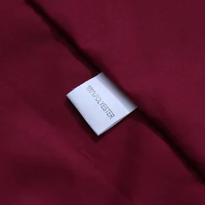 Macro view showing the 100% polyester care label on this burgundy silky fabric dress