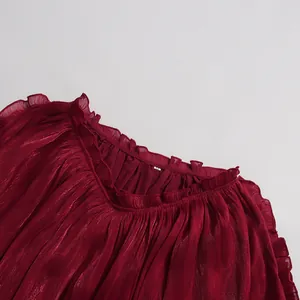Detail of burgundy mercerized pleated dress showing ruffled V-neckline and shiny fabric texture