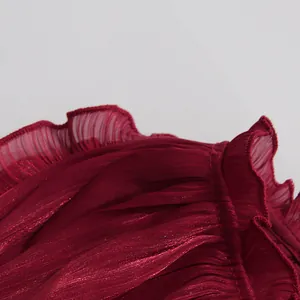 Macro shot of wine red shiny mercerized pleated fabric featuring delicate ruffled edges