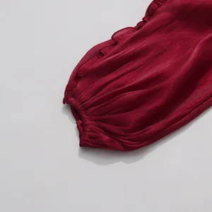 Macro detail showing the ruffled sleeve cuff on a burgundy shiny mercerized fabric dress