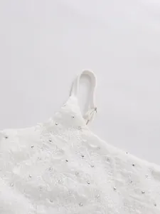 Close-up of white lace dress strap and bodice with sparkling rhinestone embellishments.