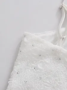 Macro view showing the intricate white lace and rhinestone detail of this dress