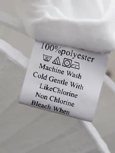 Detailed macro view of the care label on a white 100% polyester French style dress