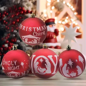 Vista detallada de bolas de Navidad rojas con motivo del belén blanco y texto JOY