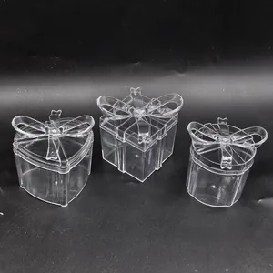 Close-up of three transparent plastic gift boxes with bow-knot lids in different shapes.