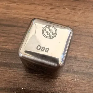 Nahaufnahme eines Food Decision Dice aus Edelstahl mit BBQ-Gravur auf Holzgrund