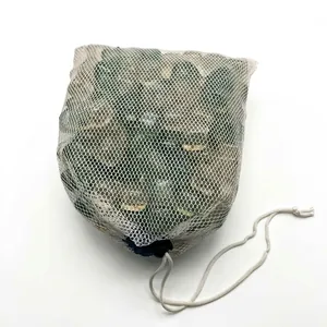 Close-up of green reusable plastic ice cubes in a white mesh drawstring bag
