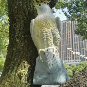 Realistische Greifvogel-Attrappe zur Vogelabwehr an einem Baumstamm im Garten