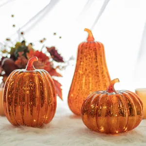 Set of three orange mercury glass style LED pumpkin decorations on white faux fur