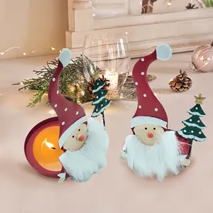 Détail de bougeoirs gnomes en métal rouge avec des accents de sapin de Noël festif