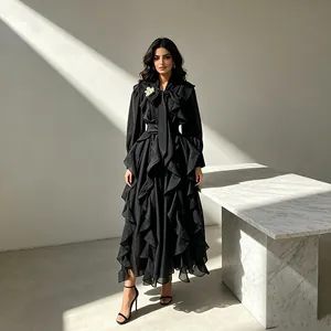 Full-length view of a model in a luxury black chiffon maxi dress with ruffled layers and a bow-tie neck