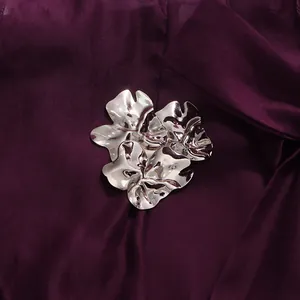 Close-up detail of a decorative metallic flower ornament on dark purple chiffon fabric
