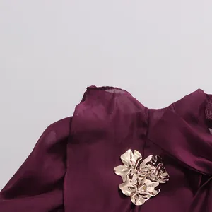 Detail of plum chiffon dress neckline with gold metallic floral decorative ornament