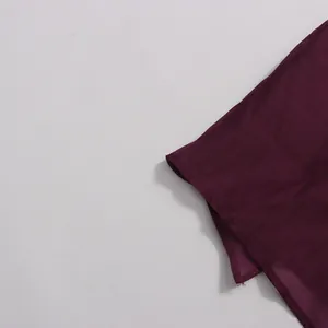 Close-up of dark burgundy chiffon fabric texture and hem detail of an elegant long dress