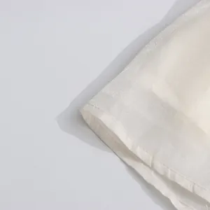 Detailed macro view of the pearlescent fabric and hem stitching of a French retro dress