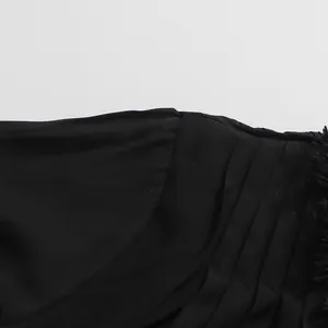 Gros plan sur les détails plissés noirs et les franges délicates d'une robe de style français.