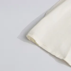 Close-up detail of the hemline and fine stitching of a white retro style dress.