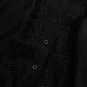 Gros plan sur la dentelle noire et les pompons d'une élégante robe rétro française.