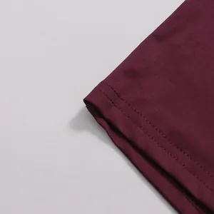 Close-up of double-stitched hem on burgundy chiffon dress showing fabric texture.