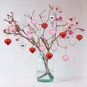 Adornos románticos en forma de corazón colgados en una rama floreciente para San Valentín