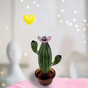 Vista macro detallada de cactus de vidrio verde artesanal con flor rosa en maceta de cristal