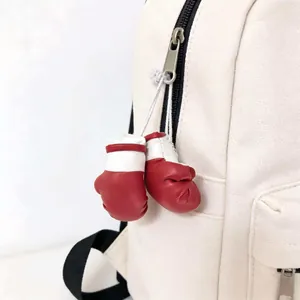 Vista dettagliata di mini guantoni da boxe rossi appesi a uno zaino in tela bianca