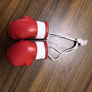 Vista dettagliata di mini ornamenti guantoni da boxe rossi con cordino bianco robusto.