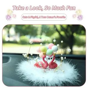 Detail view of a pink flamingo car ornament with colorful balloons and a fluffy base.