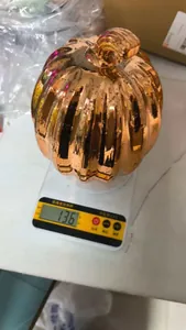 Shiny orange metallic pumpkin lamp shown on a digital scale for weight verification