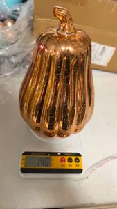 Detail showing the weight of the metallic orange pumpkin decoration on a digital scale.