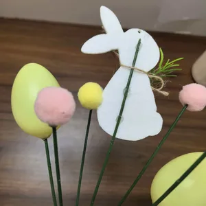 Detail of Easter floral picks with white rabbit, yellow egg, and pink pom-poms on wood background.