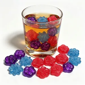 Detailed view of colorful flower-shaped reusable plastic ice cubes in a glass of tea