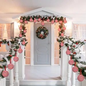 Festive red and white striped Christmas balls decorating a snowy house porch garland
