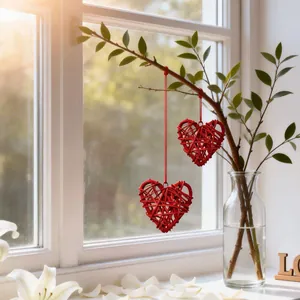 Handgefertigte rote Weidenherz-Ornamente, die an einem natürlichen grünen Zweig hängen.