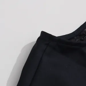Primer plano de las costuras finas y el encaje en el hombro de un vestido azul marino sin mangas.