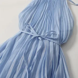 Close-up of light blue pleated dress with tie-waist detail and soft fabric texture.