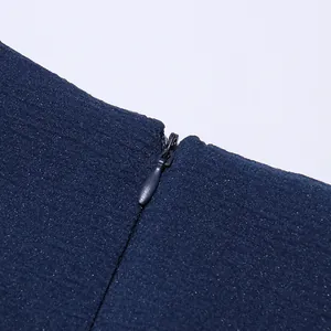 Macro close-up detail of the invisible zipper on a navy blue ruffled mini dress
