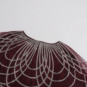 Primer plano del bordado de pedrería en el escote del vestido de tul burdeos.