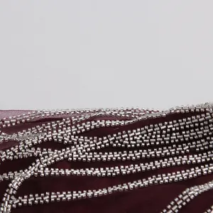 Primer plano de tela de malla roja vino con bordado de cuentas plateadas brillantes.