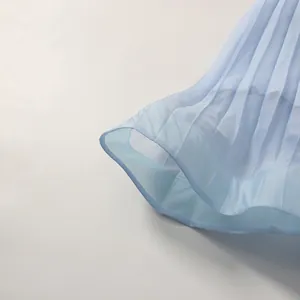 Close-up of light blue pleated dress hem showing fabric texture and pleat details.