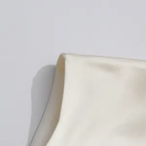 Detalle de la tela de satén lisa y las costuras de un vestido color crema sin mangas