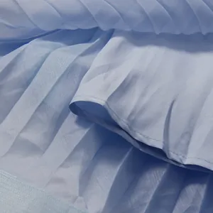 Detailed close-up of light blue pleated fabric texture on ethereal summer dress.