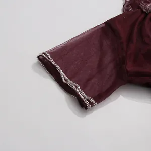 Detalle de la manga de malla color burdeos con un ribete de pedrería plata elegante
