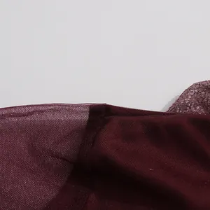 Detalle de cerca de un vestido de malla plisada granate con textura de tela delicada