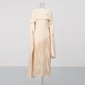 Detail van een abrikooskleurige avondjurk in cape-stijl met een lange elegante franjezoom