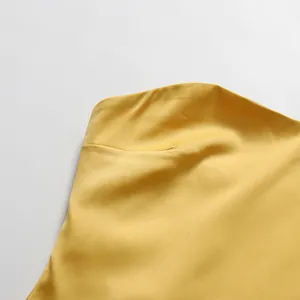 Macrodetail van de gladde gele satijnen stoftextuur op een elegante designerjurk