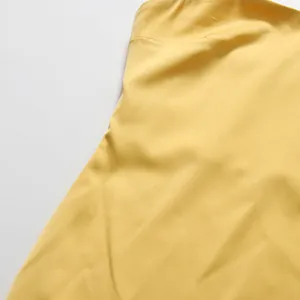 Detailopname van gele satijnen stof met gladde textuur en een luxe, hoogwaardige afwerking.