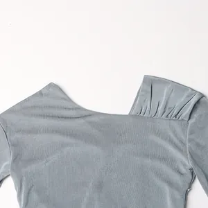 Primo piano dell'elegante scollatura a pieghe asimmetrica di questo abito in maglia grigio