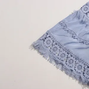 Détail d'une robe bleu clair avec broderie florale ajourée et bordure à franges